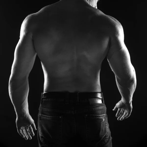 Male athlete bodybuilder posing on black background