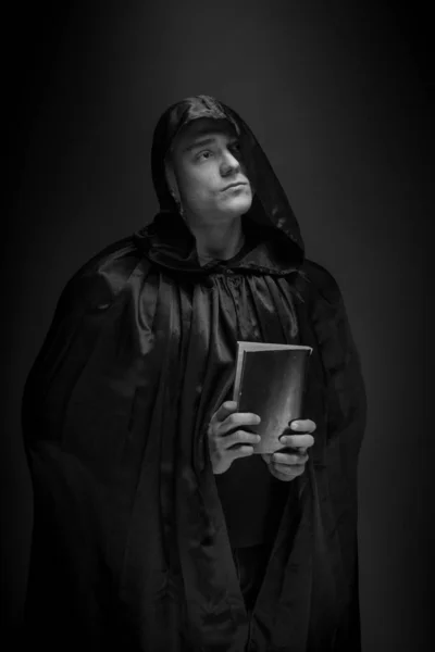 portrait of a brutal young man in a black robe posing in studio