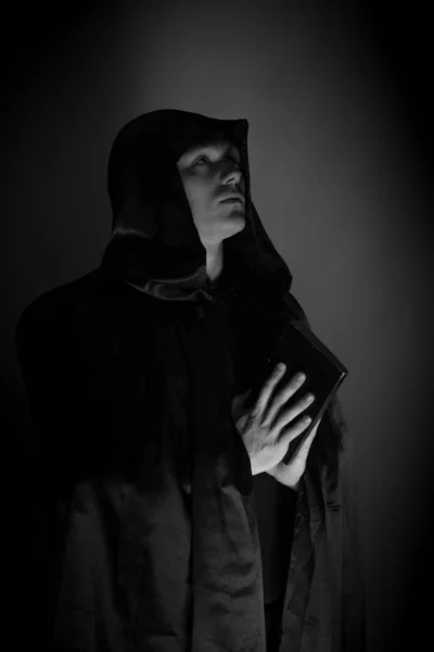 portrait of a brutal young man in a black robe posing in studio