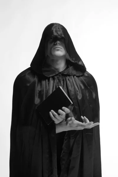 portrait of a brutal young man in a black robe posing in studio