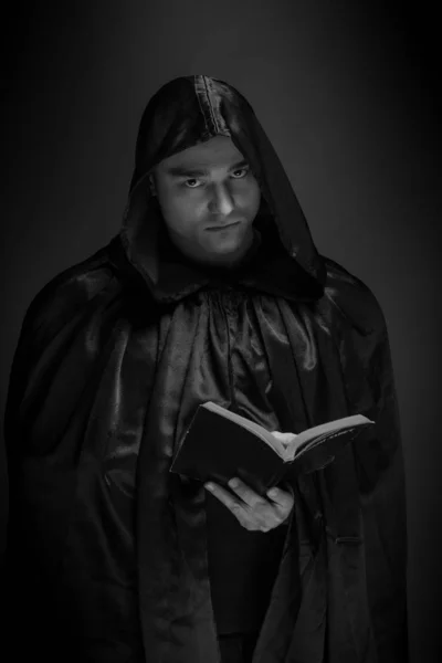 portrait of a brutal young man in a black robe posing in studio
