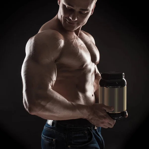 Male athlete bodybuilder posing on dark background