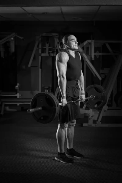 Young male athlete bodybuilder posing and doing sports exercises in the gym