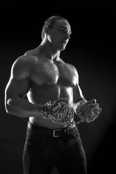 Male athlete bodybuilder posing on black background