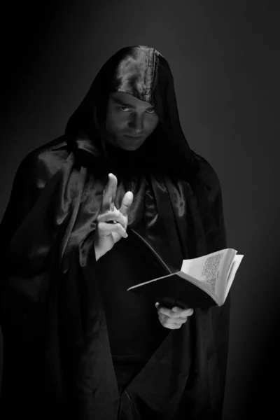 portrait of a brutal young man in a black robe posing in studio