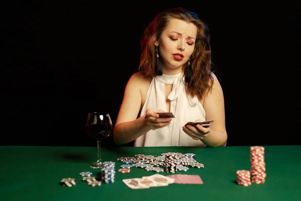 young lady in white blouse playing solitaire and posing on dark background