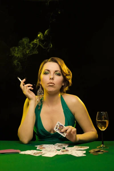 young lady in green dress playing solitaire and posing on dark background