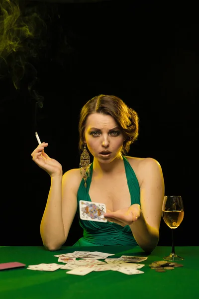 young lady in green dress playing solitaire and posing on dark background