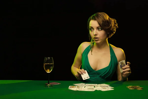 young lady in sexy dress playing solitaire and posing on dark background