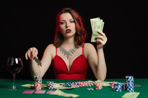 young lady in red dress playing solitaire and posing on dark background