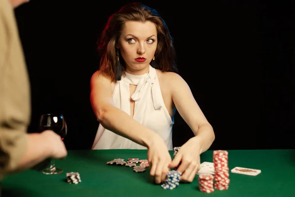 young lady in white blouse playing solitaire and posing on dark background