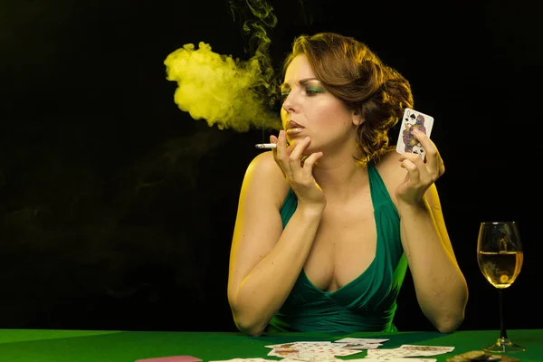 young lady in green dress playing solitaire and posing on dark background