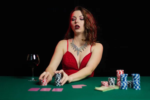 young lady in red dress playing solitaire and posing on dark background