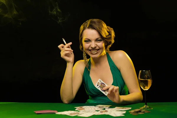 young lady in green dress playing solitaire and posing on dark background