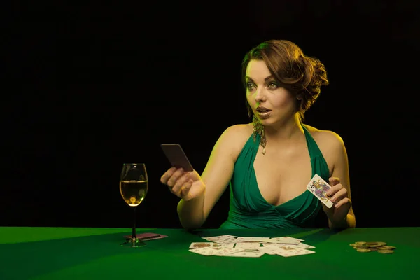 young lady in sexy dress playing solitaire and posing on dark background