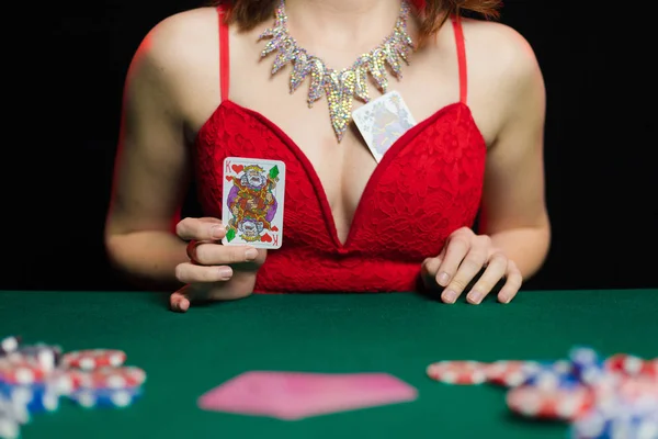 young lady in sexy dress playing solitaire and posing on dark background