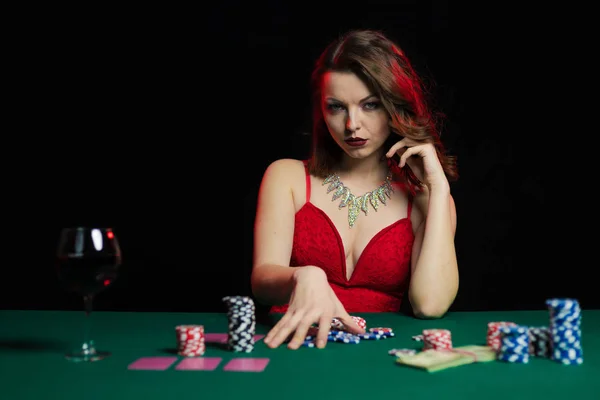 young lady in red dress playing solitaire and posing on dark background