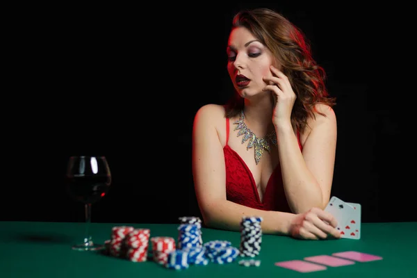 young lady in red dress playing solitaire and posing on dark background