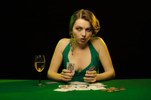 young lady in sexy dress playing solitaire and posing on dark background