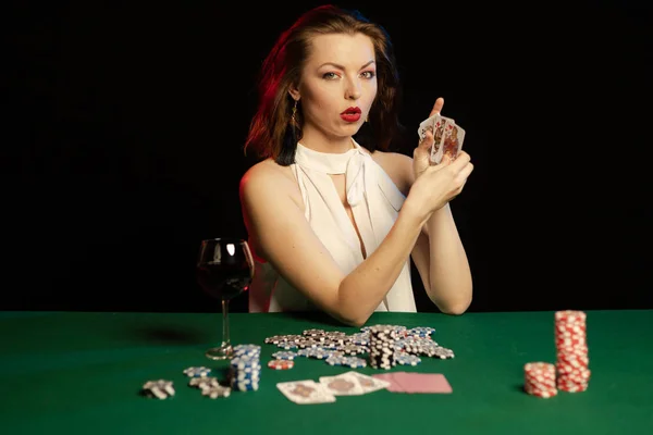 young lady in white blouse playing solitaire and posing on dark background