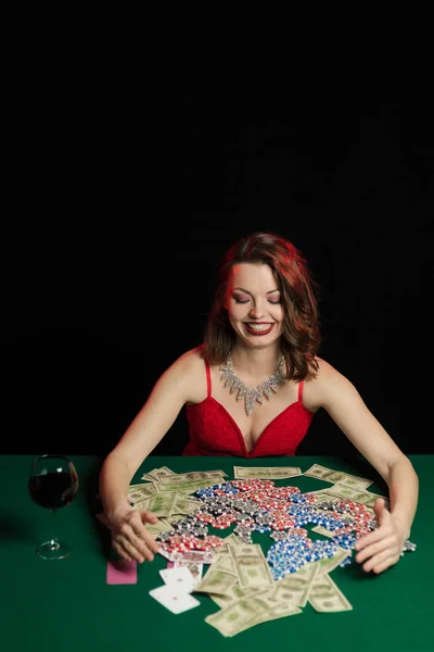 young lady in red dress playing solitaire and posing on dark background