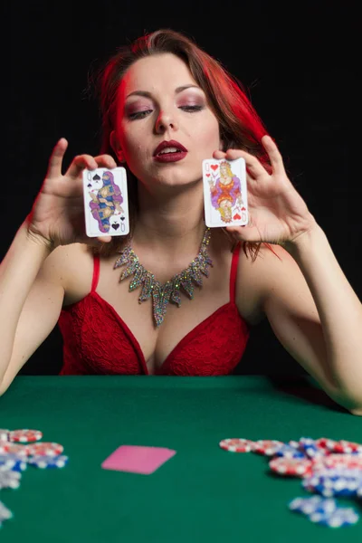 young lady in sexy dress playing solitaire and posing on dark background