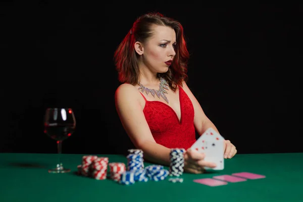young lady in red dress playing solitaire and posing on dark background