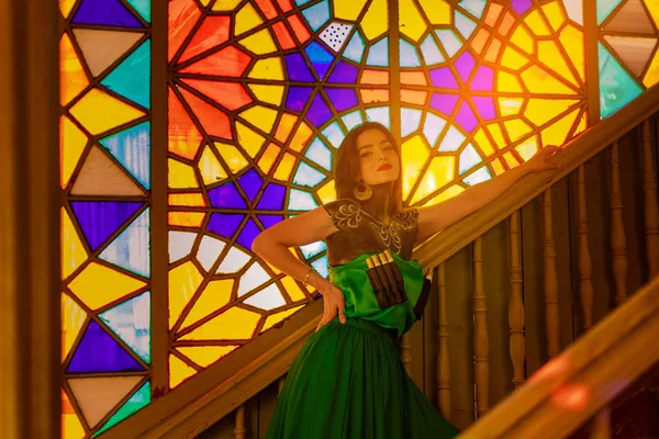 young beautiful woman in green oriental dress posing in old house