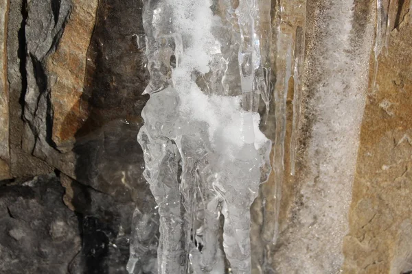 Icicles hanging on a ledge with rocky bacground — Stock Photo, Image