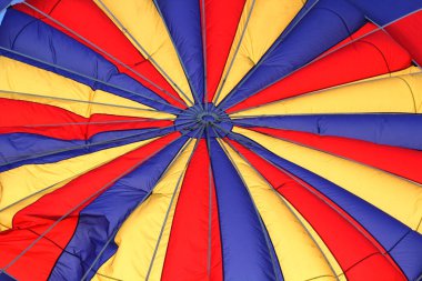 Sıcak hava balonu çeşitli renk ve çizgilere sahip kumaş desenleri şişirirken veya uçuşun başlarken.