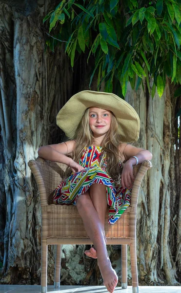 熱帯の木の背景にわら帽子の小さな女の子 — ストック写真
