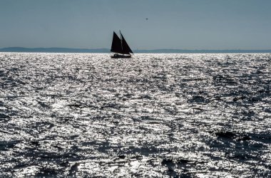 Okyanusta ufukta bir yelkenlinin silueti.