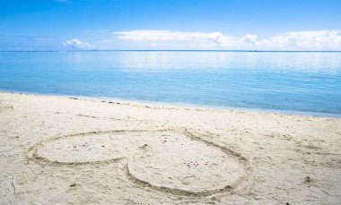 Kalp simgesi mavi gökyüzü ile kum plajındaki