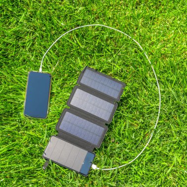 Çimlerin üzerinde güneş enerjisiyle bir cep telefonunu şarj etmek