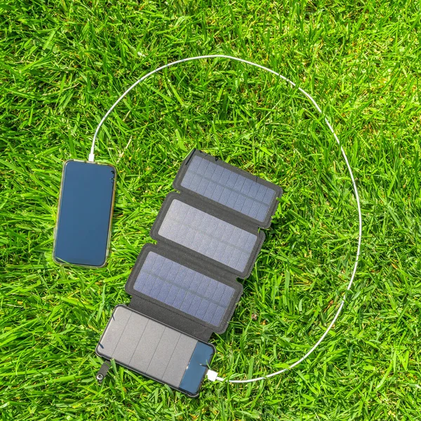 Aufladen Eines Mobiltelefons Mit Solarenergie Auf Gras Stockfoto