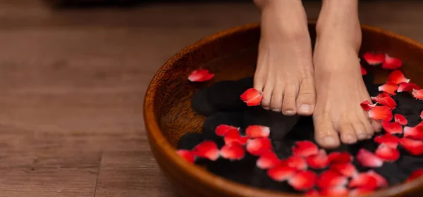 Close-up shot van een vrouw voeten ondergedompeld in water met bloemblaadjes in een wo — Stockfoto