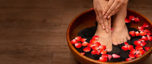Nahaufnahme einer Frau Füße in Wasser getaucht mit Blütenblättern in eine Wanne — Stockfoto