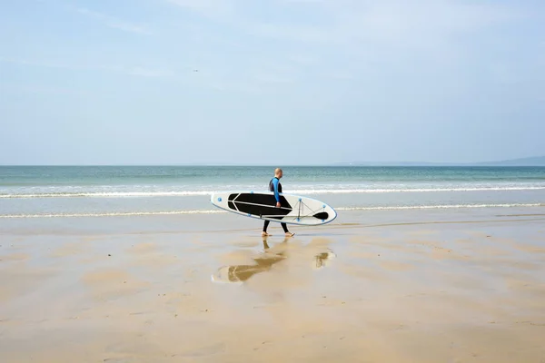 冲浪者步行与板在巴利巴宁海滩在狂放的大西洋方式 — 图库照片
