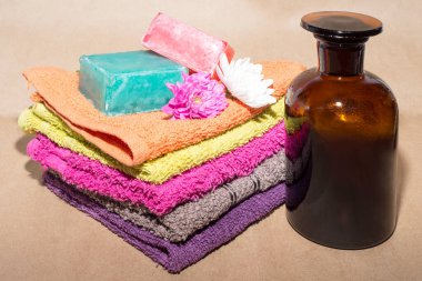 çeşitli gölgelerdeki yüz örtülerinin üzerine çiçekler ve şişeyle sabun.