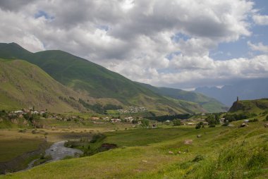 Yeşil çim ve mavi gökyüzü ile süslenmiş bir köy bakan bir güzel dağ manzarası