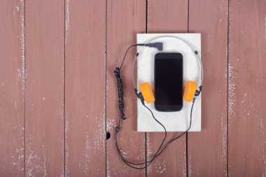 Bilim ve eğitim - kulaklık, akıllı telefon ve kitap Audiobook stil üstten görünüm ahşap masa arka plan üzerinde.