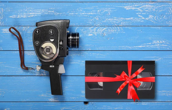 ビンテージの携帯ムービー フィルム カメラのビデオテープ Vhs プレゼント青い木製の背景に赤の弓を縛ら — ストック写真