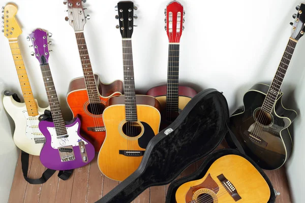 Musical instrument - lot of hard case, acoustic guitars on a white and wood background.