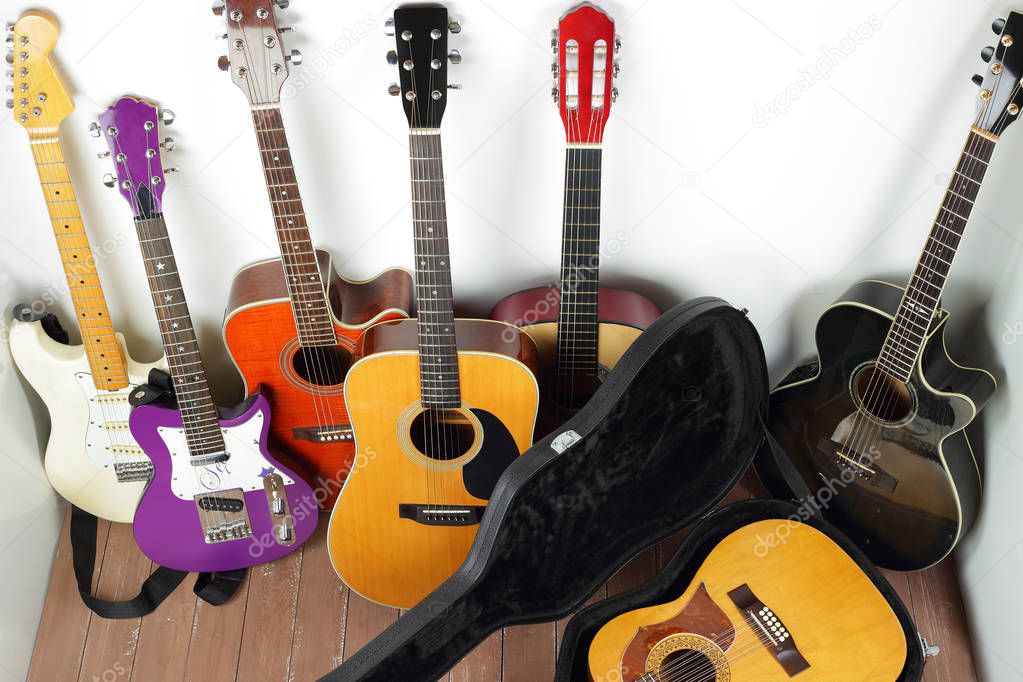 Musical instrument - lot of hard case, acoustic guitars on a white and wood background.