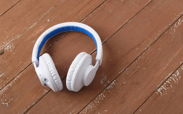 Musikinstrumente - weiße und blaue drahtlose Kopfhörer-Holzrücken — Stockfoto