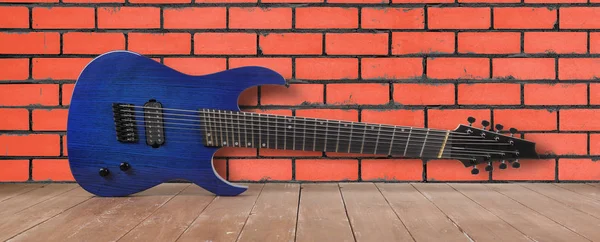 Μουσικό όργανο-μπλε 8-srtings ξύλο κιθάρας και τούβλο πίσω — Φωτογραφία Αρχείου