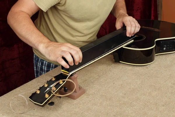 Reparatur und Service der Gitarre - Arbeiter schleift schwarzen Gitarrenhals — Stockfoto