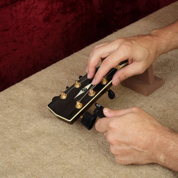 Riparazione e assistenza della chitarra - Lavoratore fissare un nuovo corde acustiche nere — Foto Stock