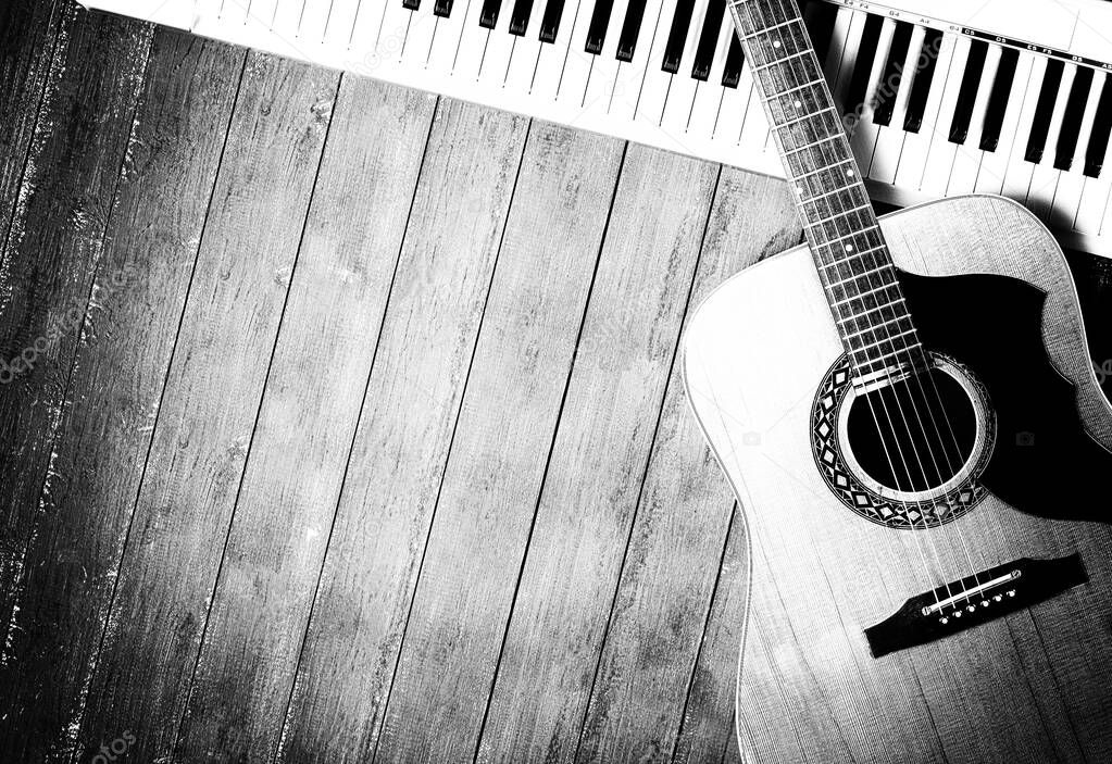 Musical instrument - Sloseup MIDI piano 61 key keyboard and vintage acoustic guitar on a wooden background monochrome