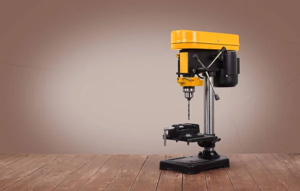 Metal işleme aracı - Ahşap bir masa üzerinde sarı yeni matkap presi ve kahverengi bir arka plan.
